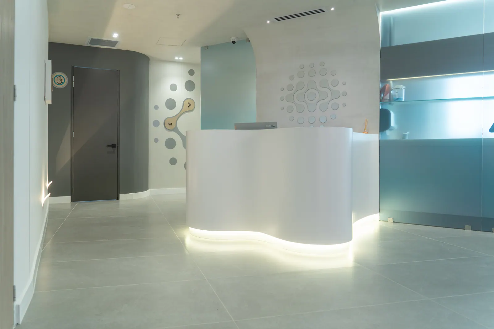 Regen Cord partner clinic — illuminated curved reception desk with cell-inspired wall art, Pereira Colombia